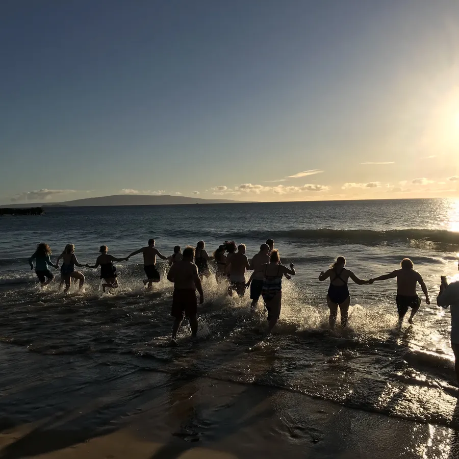 Silhouettes running into the ocean at sunrise
