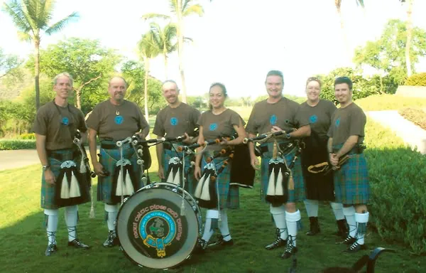Band members lined up on a lawn behind the crest drum