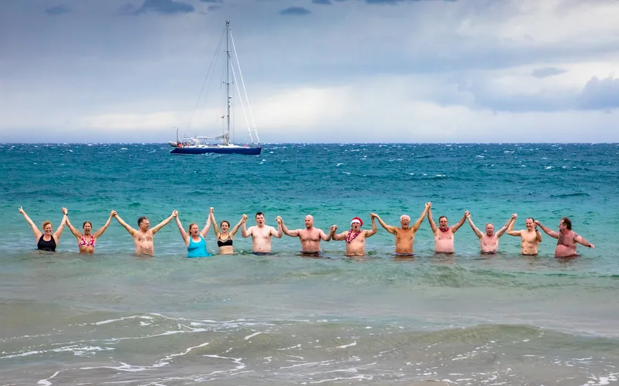Band members holding hands in a line in the ocean