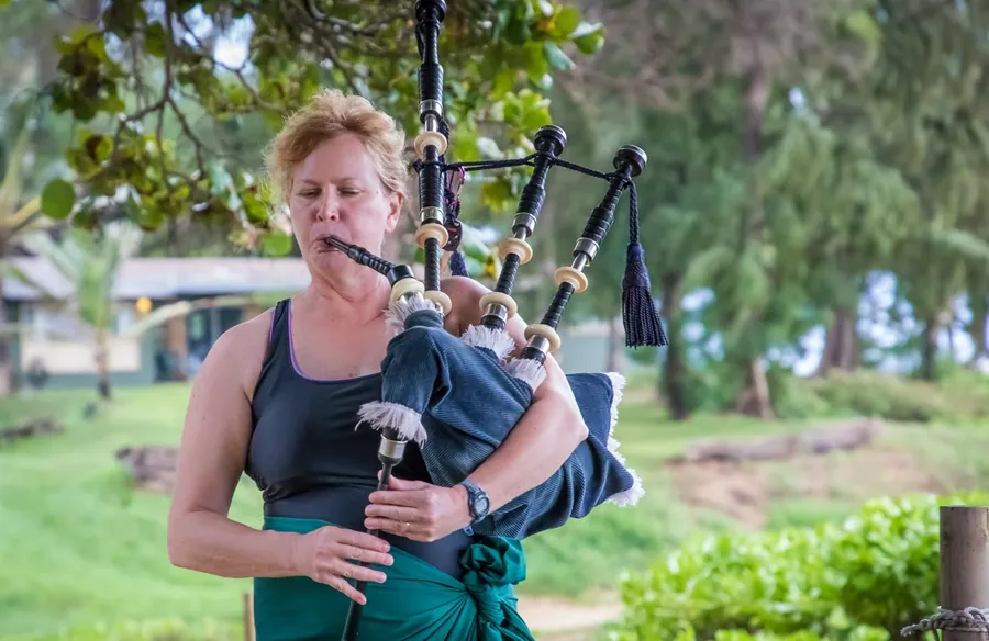 A piper playing outdoors under the trees