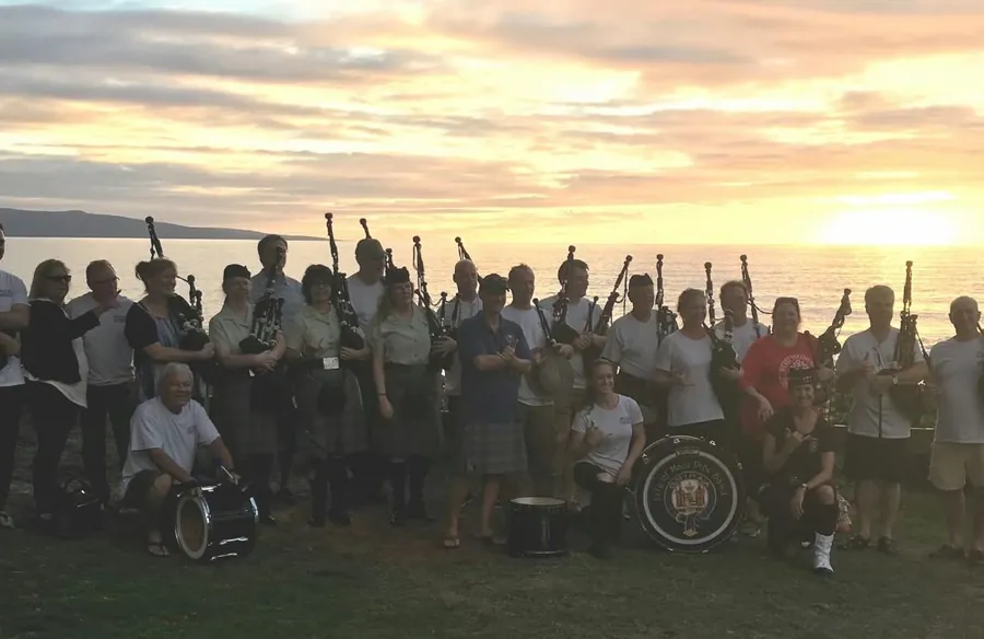 A big group of pipers and drummers at sunset