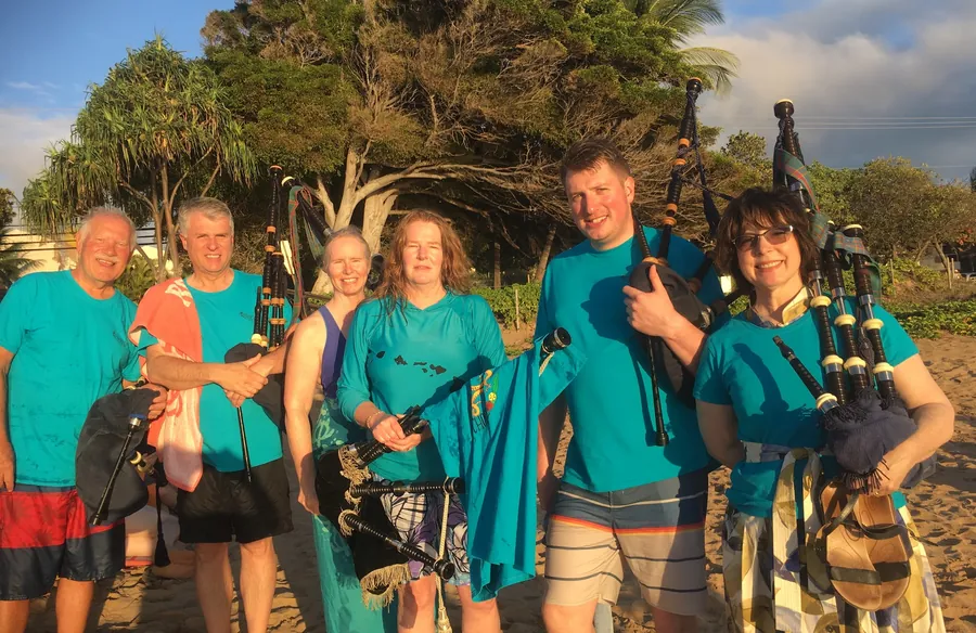 Students with pipes smiling on the beach at sunrise